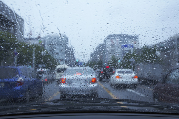 Driving in heavy rain — view from inside the car through a rain-covered windshield.